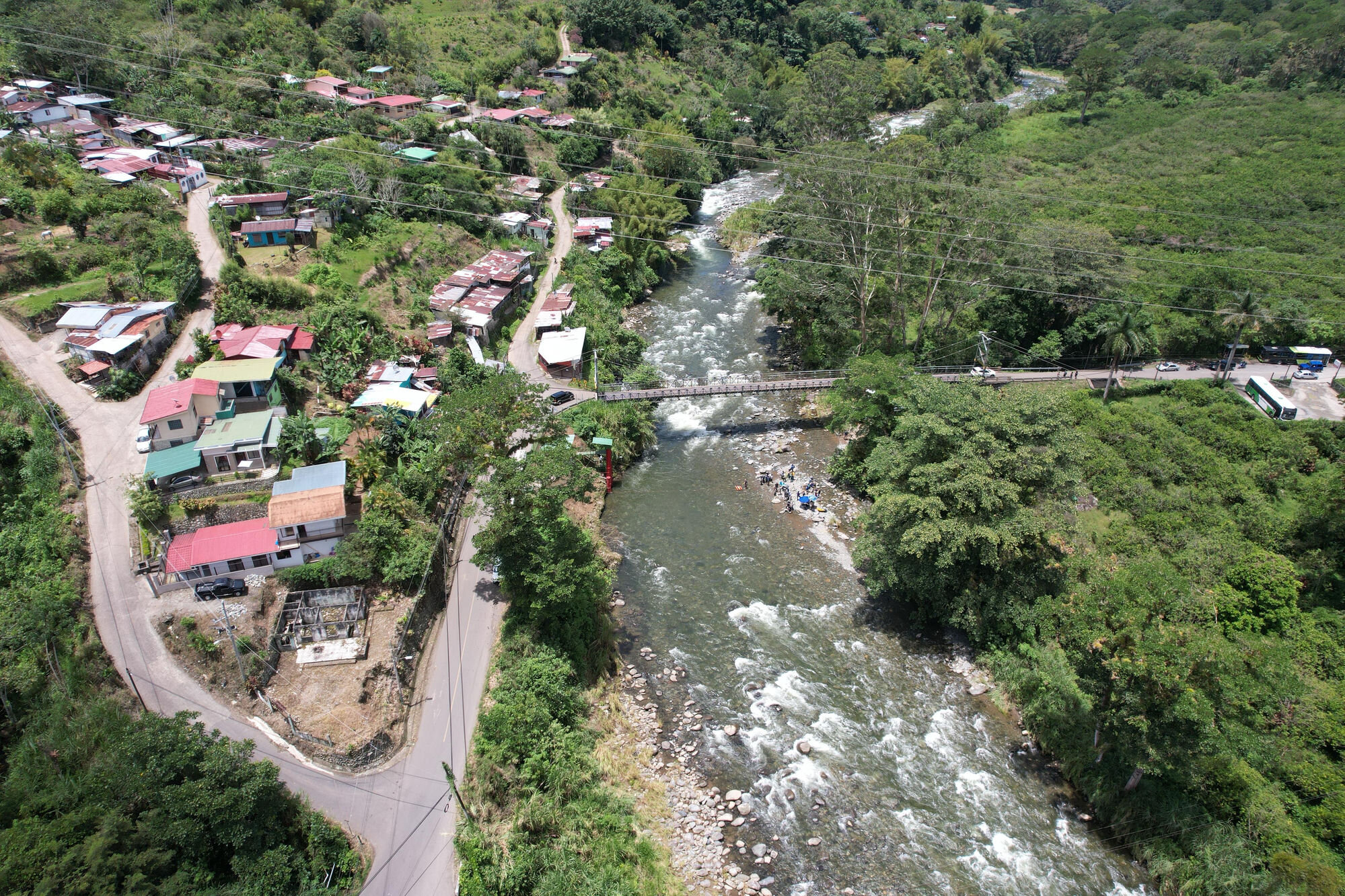 Drone view of the Río Grande de Orosí, showing the footbridge and the team gauging the river below